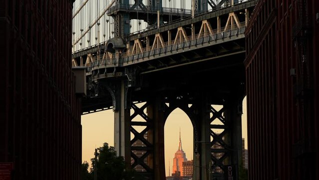 New York, USA - 3 September 2023: 4K wide angle video during a sunset over New York, view from Dumbo area in Brooklyn with Empire States landmark building under Manhattan Bridge.