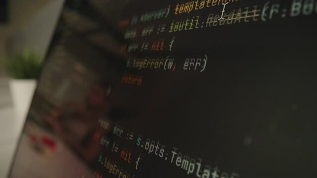 Programmer scrolls programming code on computer screen