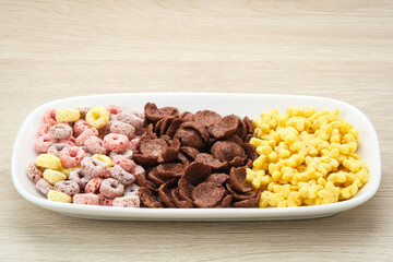 Various Cereal for breakfast on glass bowl, chocolate flakes, colorful flakes, and honey star.
