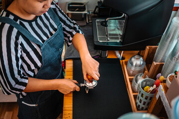 Barista holding portafilter and coffee tamper making an espresso coffee in cafe