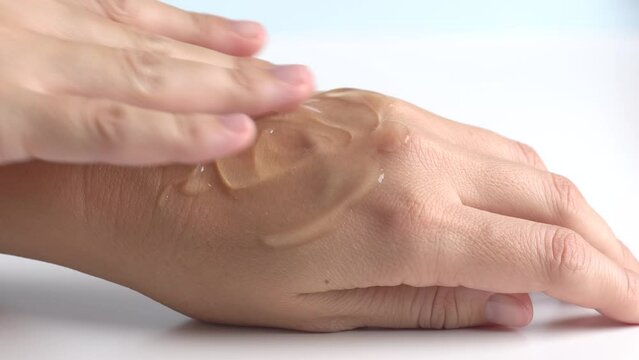 Female hands care. Close up of woman applying serum gel on hand skin. Serum oil with hyaluronic acid applied by a woman's hand, skin care cosmetics, moisturizing gel.