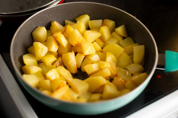 Golden brown potato cubes sizzling on a stovetop skillet