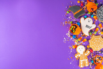 Obraz na płótnie Canvas Bright colorful Halloween gingerbread cookies and sweet background. Homemade biscuits with cookie cutters, sugar sprinkles and candies. High-colored Halloween treats flat lay top view copy space