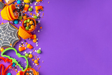 Bright colorful Halloween gingerbread cookies and sweet background. Homemade biscuits with cookie cutters, sugar sprinkles and candies. High-colored Halloween treats flat lay top view copy space