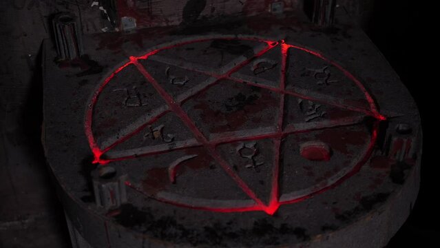 Close-up of two people removing a dirty rag from a table with a pentagram depicted. A pentagram with fire in a dark room. Quest.