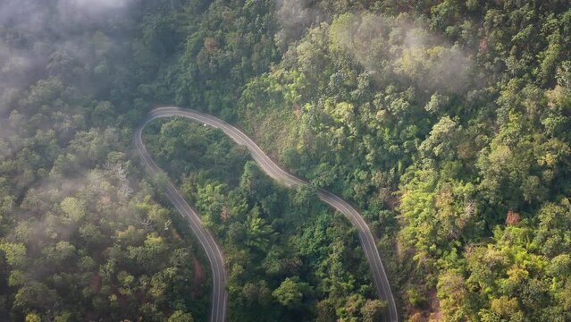 Aerial shot over a curvy road in the mountains with motorbike