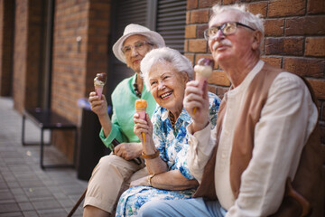 Portrait of three senior friends in the city, eating ice cream on a hot summer day.