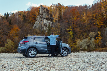 man car traveler stop at river rocky beach enjoying the autumn forest