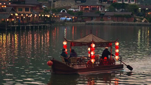 Tourists on an Asian chinese boat with red lanterns on a lake in Thailand