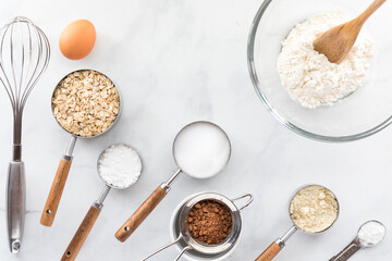 Various baking utensils and ingredients on a white marble table.