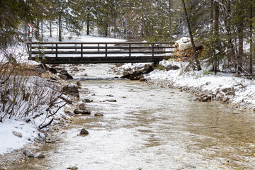 Winter landscape with the Rienz River and wooden footbridge in Toblach, Dolomites, Italy