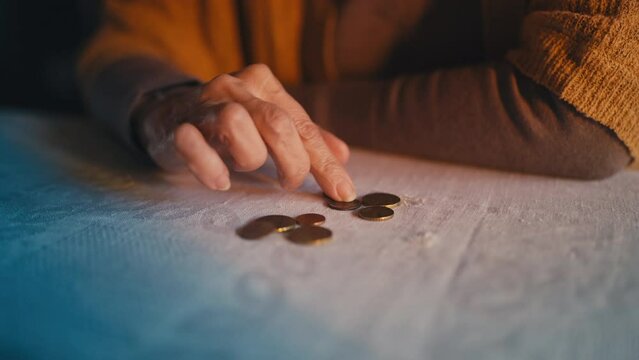 Wrinkled hands of old lady counting coins on table, financial crisis, poverty