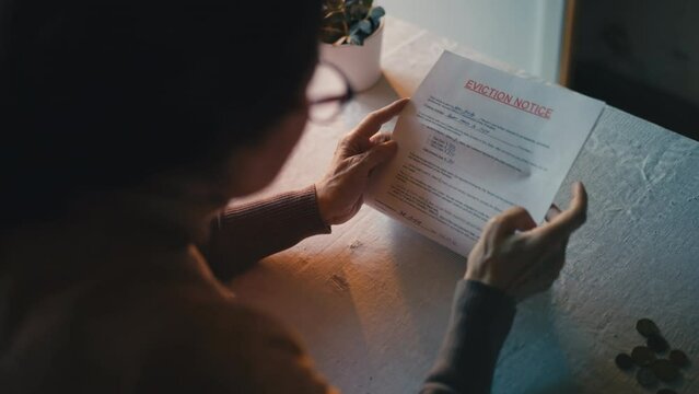 Top view of elderly woman crying with eviction notice in hands, debt problems