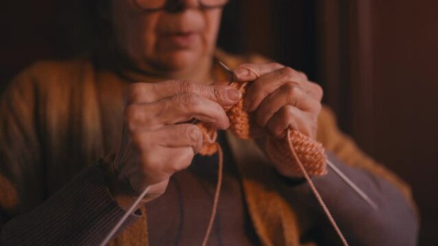 Close-up hands of senior woman thoroughly knitting training motor control skills