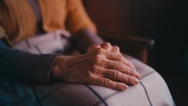 Trembling wrinkled hands close-up, lonely senior person covered with blanket