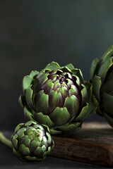 Obraz premium Green artichokes close-up.Dark background. Vertical photo.Copy space.