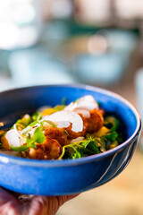 man hand hold Shrimps salad with arugula, mango and coconut in bowl