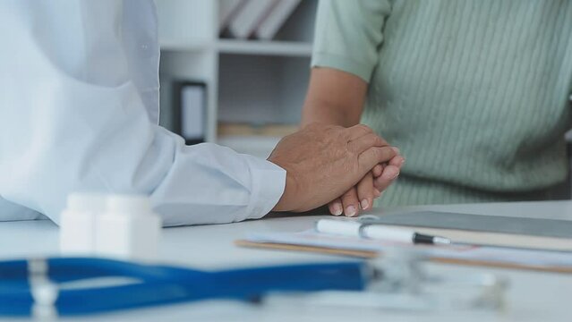 Female doctor in white coat holding hand of senior patient, giving help, comfort, psychological support, empathy at appointment. Elderly medic care, geriatric healthcare concept. Close up