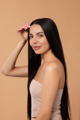 Fototapeta premium Beautiful woman with long hair on beige background