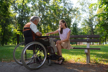 A young caregiver playing chess, talking and spending quality time with lonely senior client in the city park. Elderly healthcare and mental health. 