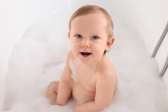 Cute little baby bathing in tub at home