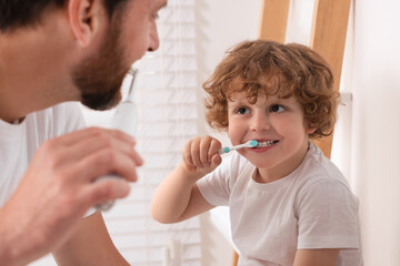 Father and his son brushing teeth together in bathroom