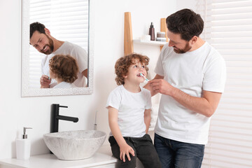 Fototapeta premium Father helping his son to brush teeth in bathroom