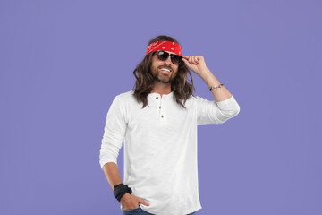 Stylish hippie man in sunglasses on violet background