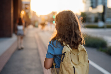 Rear view of a girl with a backpack goging to school in the morning.