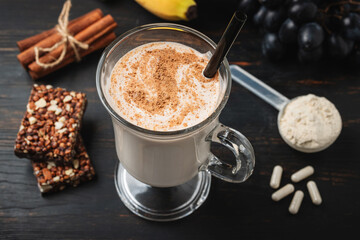 Glass of protein milkshake drink with straw and scoop of whey protein powder, white capsules of...