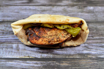 Sandwich of chicken grilled and roasted on a charcoal grill, served with grilled green peppers and...