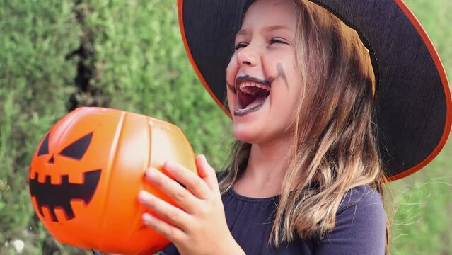 Video portrait happy face girl trick or treat Halloween excited surprise kid girl wearing dress witch hat costume party Halloween children. pumpkin basket candies, hold buckets and wait for treats