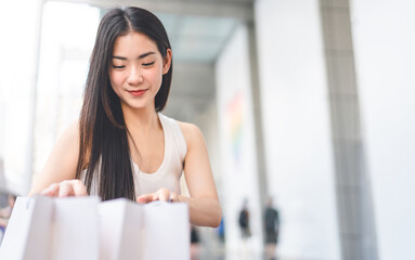 Asian woman long hair wearing white tanktop looking in shopping bag