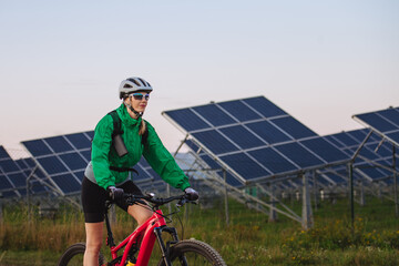 Portrait of a beautiful cyclist riding in front of solar panels at a solar farm. © Halfpoint