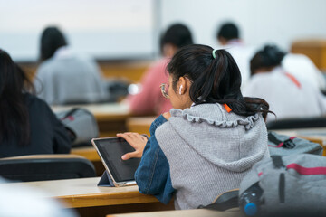 University students concentrate on doing examinations via tablet and smartphone in the classroom - obrazy, fototapety, plakaty