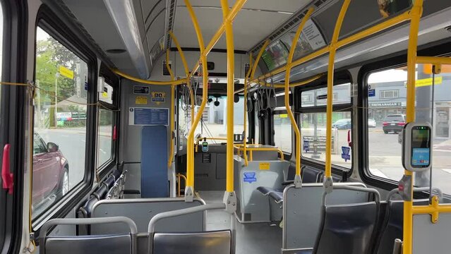 an empty bus in Canada in Vancouver seats window the bus goes between stations outside the window green leaves street. Ordinary life in British Columbia