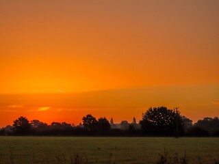 bright orange sky at sunrise over the countryside and trees