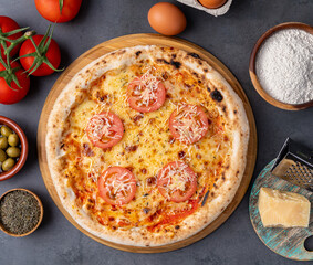 Napolitan pizza with tomatoes, olive oil, eggs and flour over wooden table