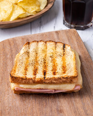 Cheese and ham sandwich with potato chips and soda