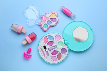 Eye shadow palette and other decorative cosmetics for kids on light blue background, flat lay