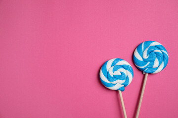 Sticks with bright lollipops on pink background, flat lay. Space for text