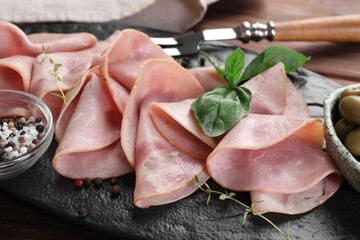 Tasty ham with basil, sea salt and peppercorns served on table, closeup