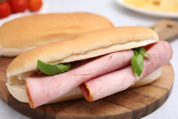 Delicious sandwich with ham and basil on table, closeup
