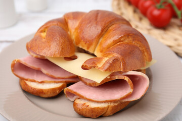 Obraz na płótnie Canvas Tasty crescent roll with ham and cheese on table, closeup