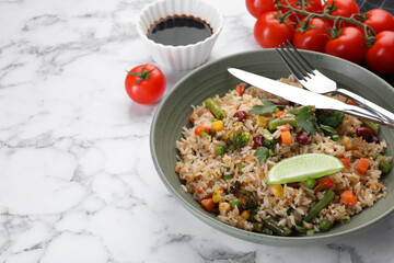 Tasty fried rice with vegetables served on white marble table, closeup. Space for text