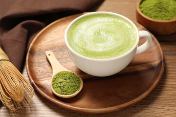 Cup of fresh matcha latte and powder on wooden table