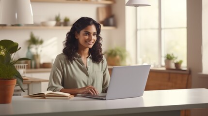 Fototapeta premium Indian business woman working on a laptop in a bright, open workspace. A young Indian student or remote teacher is working in online education, flexibility of remote work. Generative AI