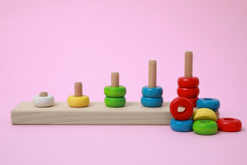 Stacking and counting game wooden pieces on pink background. Educational toy for motor skills development