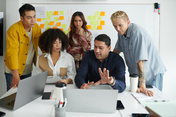 Team gathered in front of opened laptop to discuss product presentation