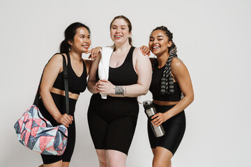 Three joyful fitness women posing together isolated over white background